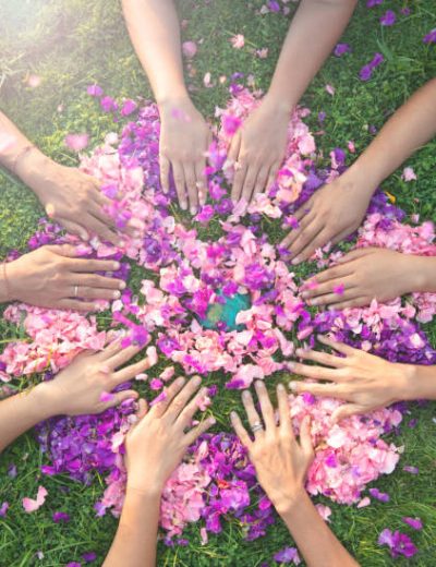Many hands touch each other on a bed of flowers